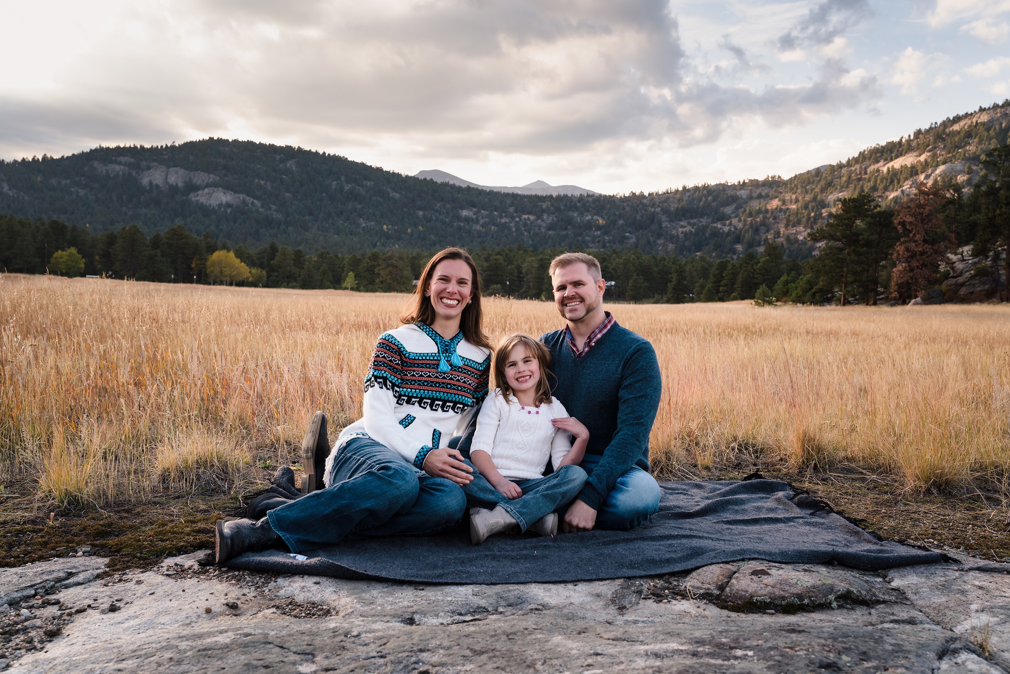 Family sitting in a field at alderfer 3 sisters park in evergreen Colorado