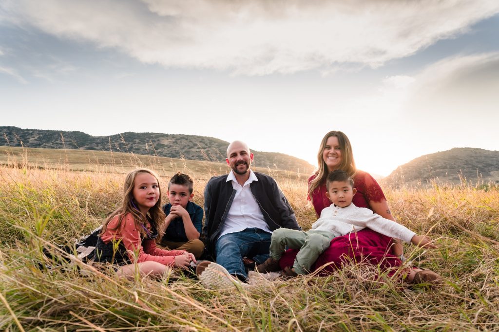 Family of 5 sitting in a field